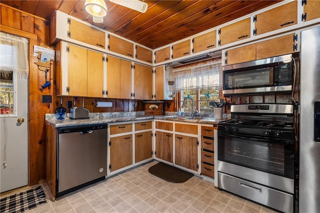 kitchen with appliances with stainless steel finishes, ceiling fan, sink, wooden ceiling, and wood walls