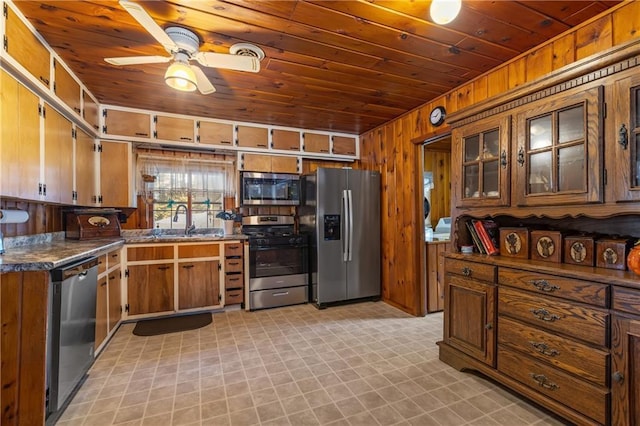 kitchen with appliances with stainless steel finishes, ceiling fan, wooden ceiling, and wood walls