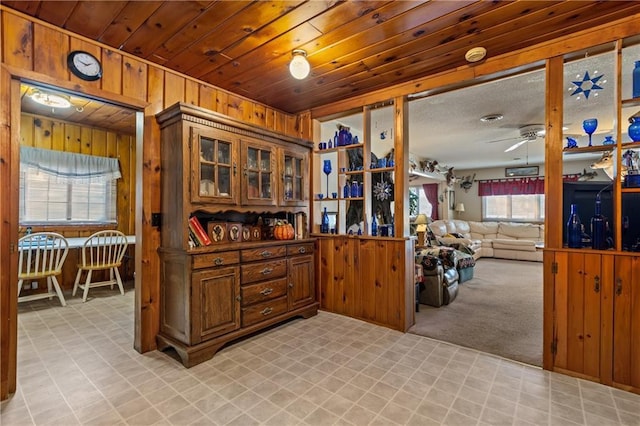 kitchen featuring ceiling fan, light carpet, and wooden walls