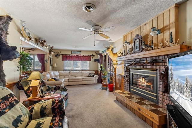 living room with a textured ceiling, ceiling fan, wood walls, and a fireplace