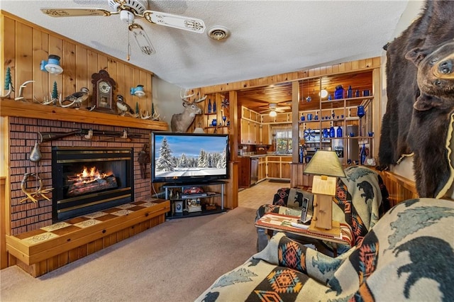 living room featuring wood walls, a textured ceiling, light carpet, and a brick fireplace