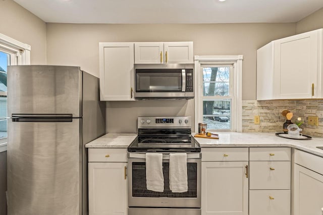 kitchen featuring white cabinets, appliances with stainless steel finishes, and light stone countertops