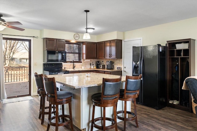 kitchen with a center island, sink, dark hardwood / wood-style floors, dark brown cabinets, and black appliances