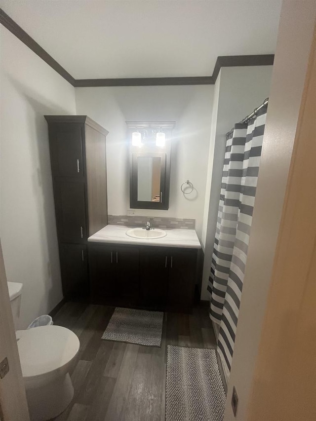 bathroom with crown molding, hardwood / wood-style floors, vanity, and toilet