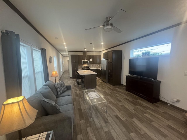 living room with crown molding, ceiling fan, and dark wood-type flooring