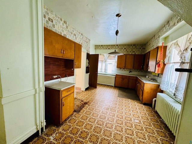 kitchen featuring pendant lighting, brick wall, sink, and radiator