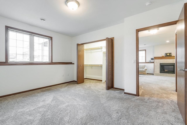 unfurnished bedroom featuring light carpet, a tile fireplace, and a closet