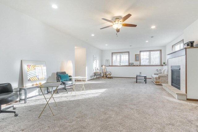 sitting room featuring ceiling fan, a tile fireplace, and light carpet