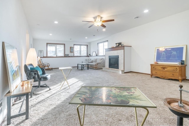 carpeted living room featuring ceiling fan and a tile fireplace