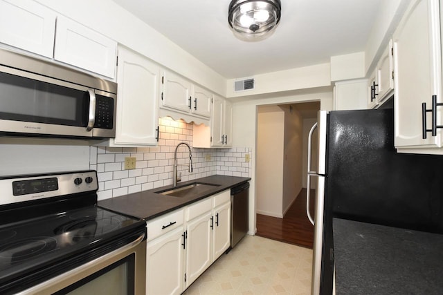 kitchen with tasteful backsplash, sink, white cabinets, and appliances with stainless steel finishes