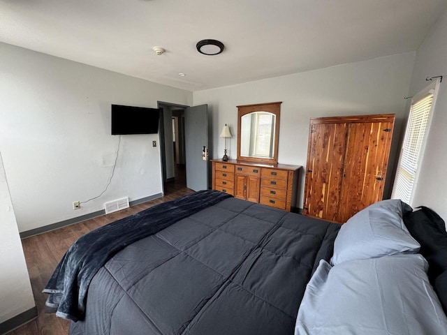 bedroom with dark hardwood / wood-style flooring and multiple windows