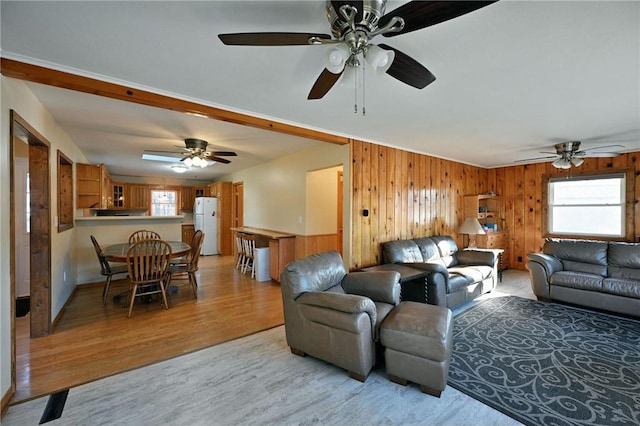 living room featuring light hardwood / wood-style flooring, ceiling fan, and wooden walls