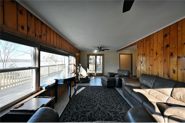 living room featuring ceiling fan, wood walls, and a water view