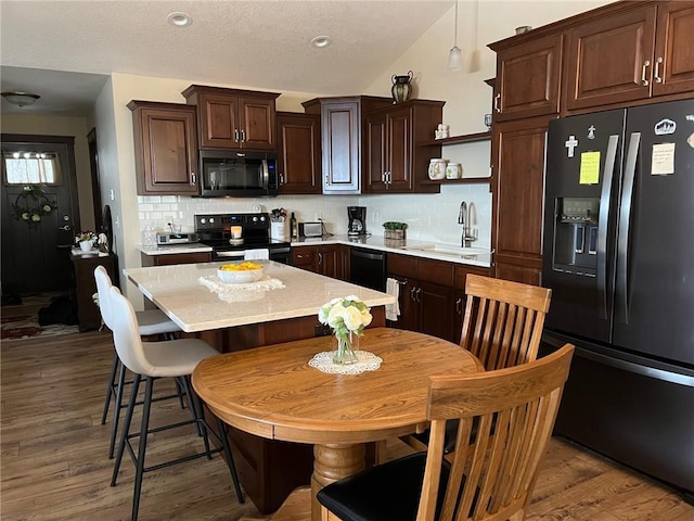 kitchen featuring sink, dark hardwood / wood-style floors, backsplash, dark brown cabinets, and black appliances