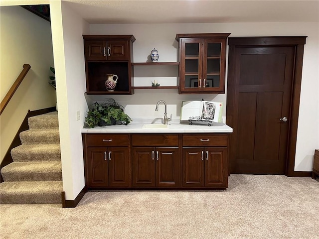 bar featuring light carpet, dark brown cabinetry, and sink