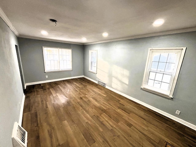 unfurnished room featuring dark hardwood / wood-style floors, ornamental molding, and a wealth of natural light