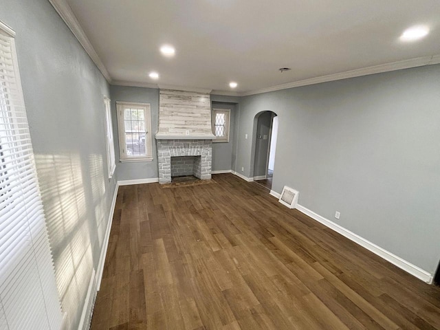 unfurnished living room featuring a large fireplace, ornamental molding, and dark wood-type flooring