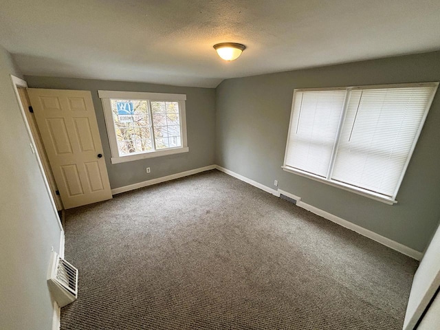 carpeted empty room with a textured ceiling