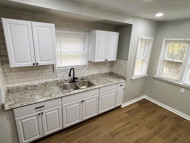 kitchen with tasteful backsplash, white cabinetry, dark wood-type flooring, and sink