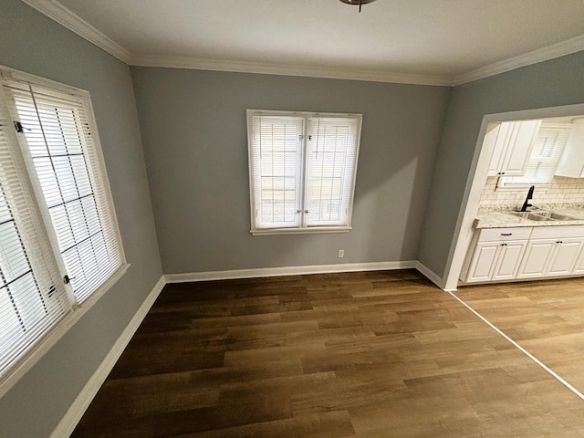 unfurnished dining area with sink, hardwood / wood-style floors, and ornamental molding