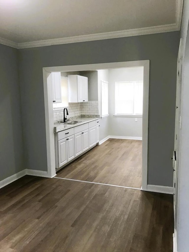 kitchen with white cabinets, decorative backsplash, ornamental molding, and sink