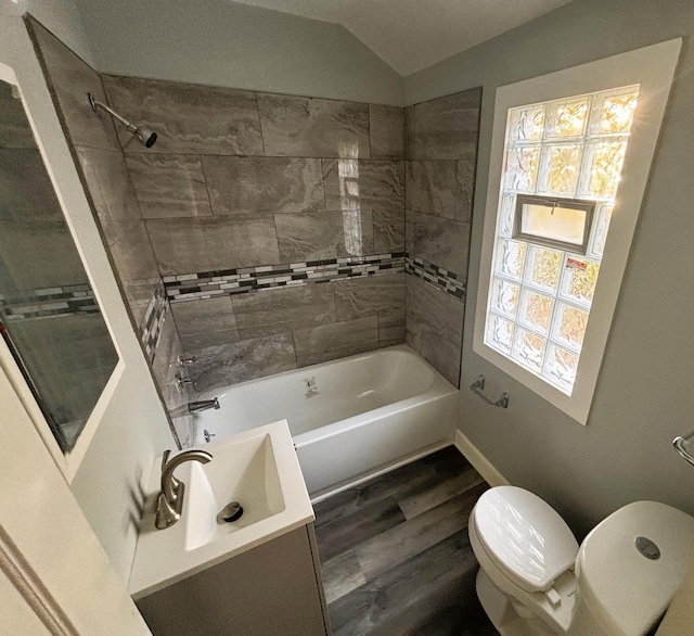 bathroom featuring hardwood / wood-style floors, vaulted ceiling, toilet, and tiled shower / bath