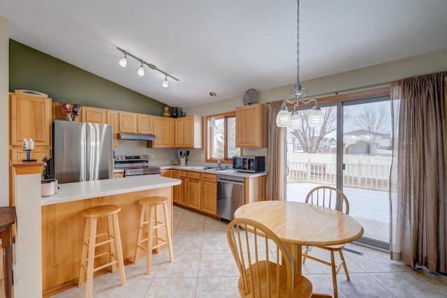 kitchen with stainless steel appliances, decorative light fixtures, vaulted ceiling, a breakfast bar area, and light tile patterned flooring