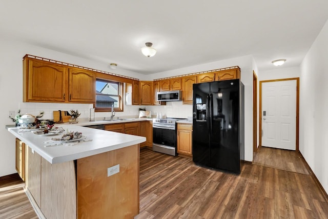 kitchen with kitchen peninsula, decorative backsplash, stainless steel appliances, dark wood-type flooring, and sink