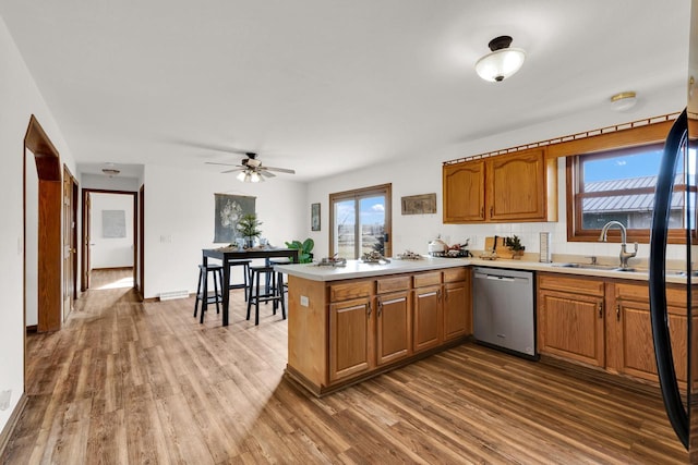 kitchen with ceiling fan, sink, stainless steel dishwasher, kitchen peninsula, and hardwood / wood-style flooring