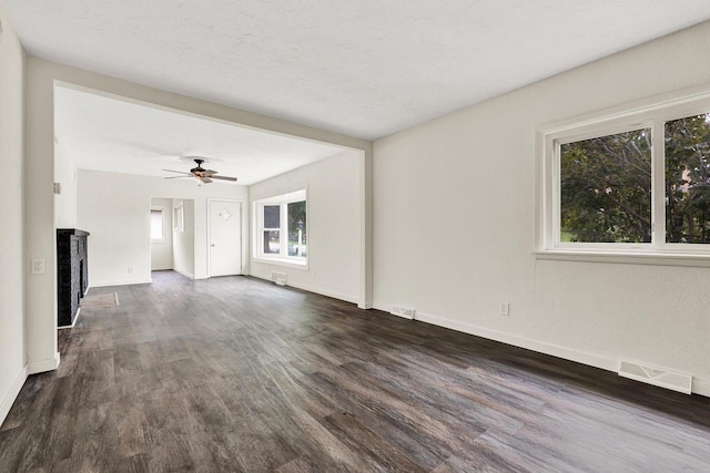 unfurnished living room featuring ceiling fan and dark wood-type flooring