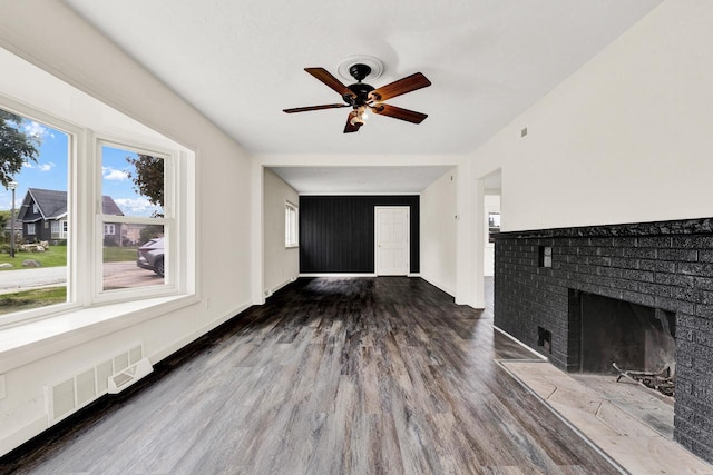 unfurnished living room with hardwood / wood-style flooring, ceiling fan, and a brick fireplace