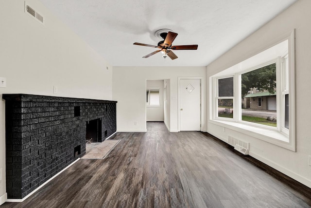 unfurnished living room featuring ceiling fan, dark hardwood / wood-style flooring, and a brick fireplace