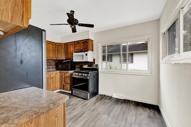 kitchen with backsplash, ceiling fan, light hardwood / wood-style floors, and appliances with stainless steel finishes