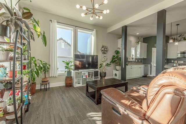 living room with sink, dark wood-type flooring, and an inviting chandelier