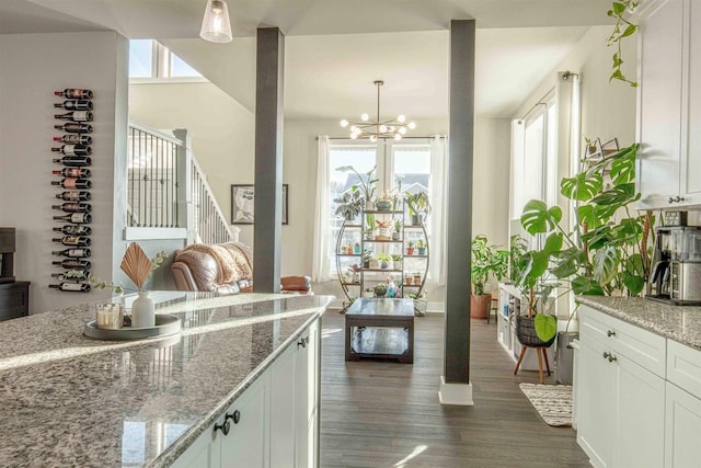 kitchen featuring white cabinets, pendant lighting, a notable chandelier, and light stone counters