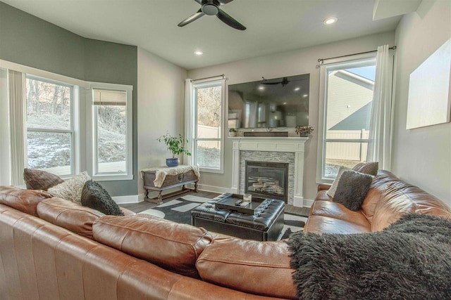 living room featuring ceiling fan, a healthy amount of sunlight, hardwood / wood-style floors, and a fireplace