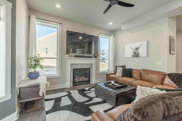 living room featuring ceiling fan, a fireplace, and wood-type flooring