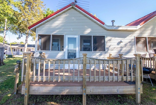 rear view of property featuring a sunroom and a wooden deck