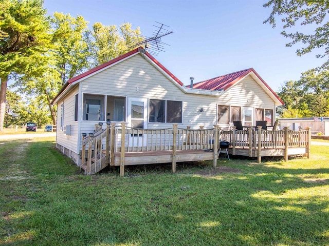 back of property featuring a lawn, a sunroom, and a deck