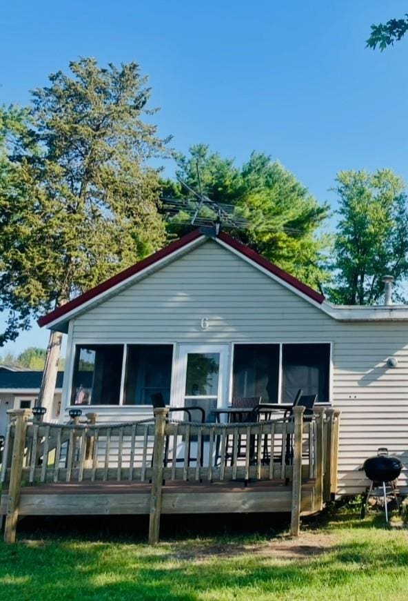 rear view of property featuring a deck and a sunroom