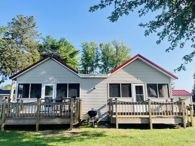 rear view of property with a lawn, a sunroom, and a deck