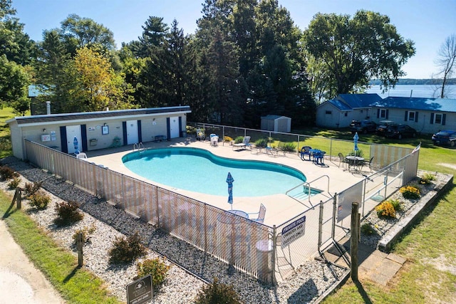 view of swimming pool with a storage shed and a patio