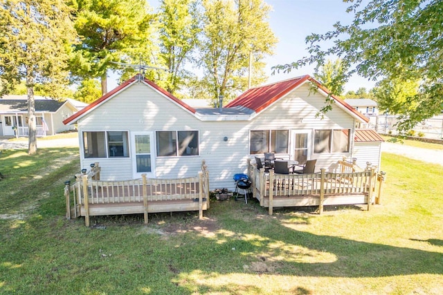 back of property featuring a lawn, a sunroom, and a deck