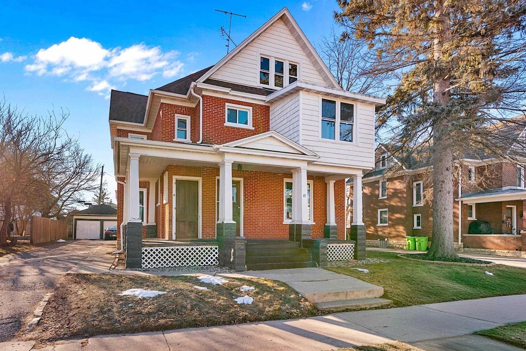 view of front of house with a porch, a garage, an outdoor structure, and a front yard