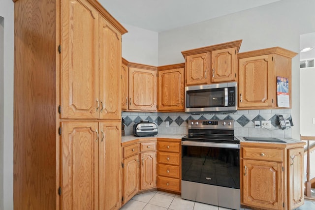 kitchen with stainless steel appliances, light tile patterned flooring, and backsplash