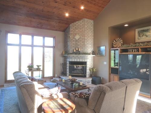 living room featuring high vaulted ceiling, wooden ceiling, and a brick fireplace