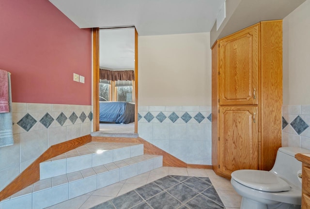 bathroom featuring tile walls, tile patterned flooring, and toilet