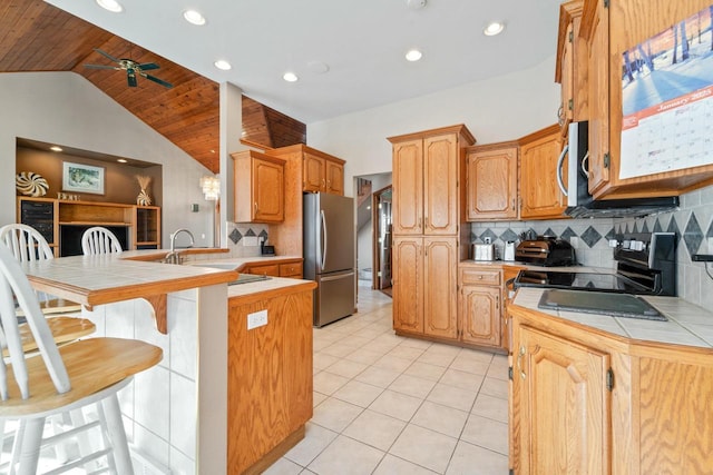 kitchen with a breakfast bar area, stainless steel appliances, kitchen peninsula, tile countertops, and decorative backsplash