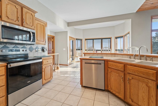 kitchen with sink, stainless steel appliances, tasteful backsplash, and light tile patterned floors