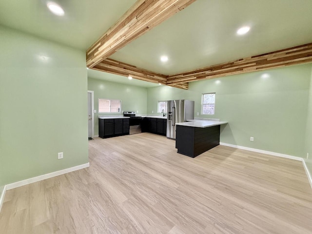 kitchen featuring sink, light wood-type flooring, beam ceiling, kitchen peninsula, and stainless steel appliances